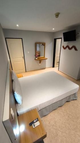 une chambre avec un grand lit blanc et une table dans l'établissement Hotel Parguito, à La Sabana