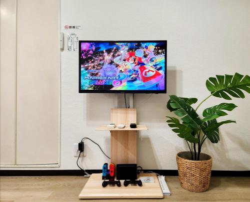 a tv on a wall with a video game on it at D,A-House OSAKA in Osaka