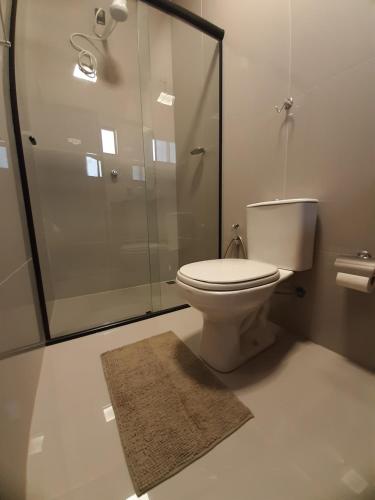 a bathroom with a shower and a toilet and a rug at Morada 1 do Jardim do Éden in Parnaíba