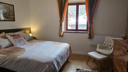 a bedroom with a bed and a window and a chair at Maison Cavalese - Polar Express in Cavalese
