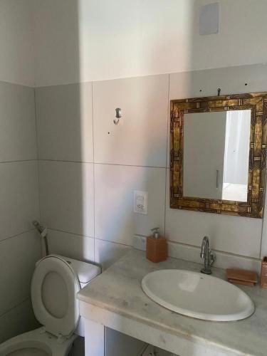 a bathroom with a sink and a toilet and a mirror at Apartamento Gute Morro - Praça Central in Cairu