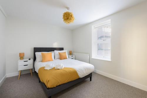 a bedroom with a bed with a yellow blanket and a window at Large 4-Bedroom House in Banbury in Banbury