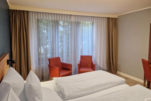 a hotel room with two chairs and a bed and a window at Garner Hotel Bochum by IHG in Bochum