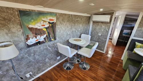 ein Wohnzimmer mit einem Tisch, Stühlen und einem Gemälde in der Unterkunft Bird Bus Chile - Descanso- Aventura - Comodidad in Chillán
