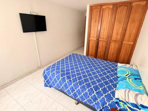 una camera da letto con un letto con una coperta blu sopra di Apartamento frente al parque infantil a Pasto