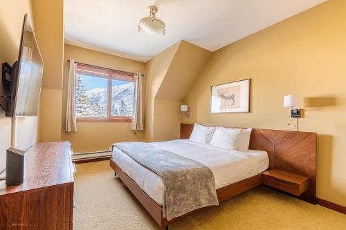 a bedroom with a bed and a window and a television at El Paraiso - Luxury Downtown Penthouse in Canmore