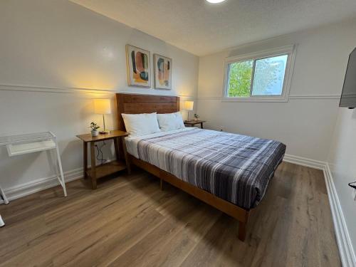 a bedroom with a bed with two tables and a window at North Barrie !D Stylish and Cozy Private Bedroom with Shared Bathroom in Barrie