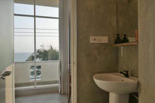 a bathroom with a sink and a window with the ocean at The Stables Oceanfront Hotel Midigama in Midigama East