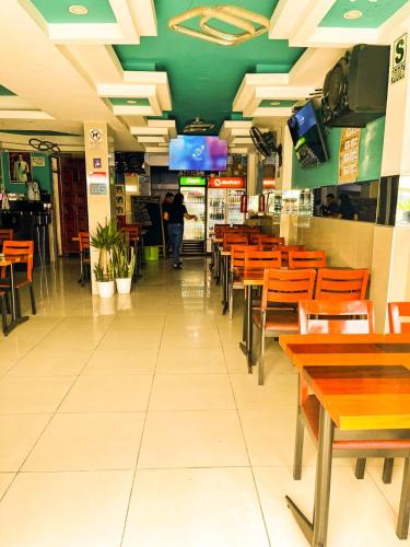 Un restaurante con mesas y sillas y una persona caminando por el pasillo. en HOSTAL PARIS MyP 3, en Lima