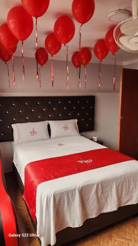1 dormitorio con globos rojos colgando sobre una cama en HOSTAL PARIS MyP 3, en Lima