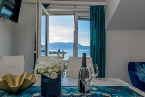 a table with a vase of flowers and wine glasses at Apartments Beach house Blace in Blace