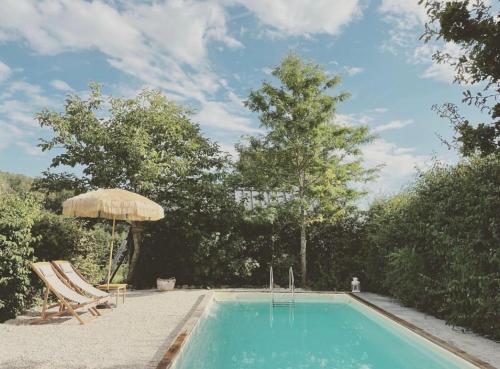 ChampignollesTraditional Apartment In The Heart Of Burgundy的一个带椅子和遮阳伞的游泳池