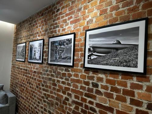 a brick wall with four pictures on it at SILESIAN LOFT Apartment in Ruda Śląska