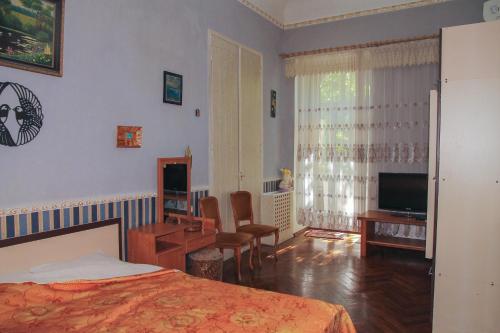 een slaapkamer met een bed, een bureau en een televisie bij Sadovaya Historical apartment in Odessa