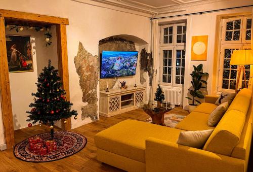 a living room with a yellow couch and a christmas tree at Leone Stays - Golden Castle Loft in Thun