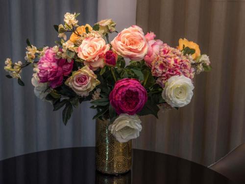 un jarrón con un ramo de flores sobre una mesa en Hôtel Mercure Paris Suresnes Longchamp, en Suresnes
