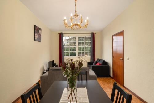 a dining room with a table with a vase of flowers at Vigário House in Câmara de Lobos