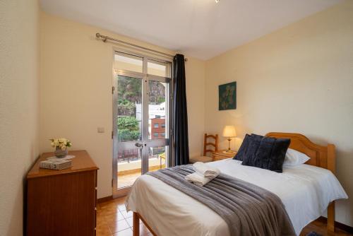 una camera da letto con un letto e una grande finestra di Vigário House a Câmara de Lobos