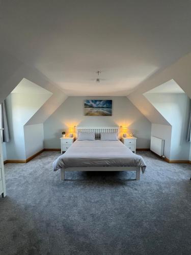 a large bedroom with a bed and two night stands at Modern timber clad house in Stornoway