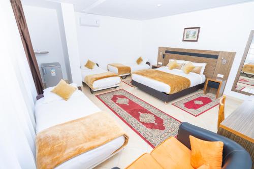 um quarto de hotel com três camas e um sofá em Tanger Med Hotel, Conference & Catering em Ghdar Defla