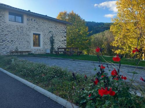 un edificio de piedra con flores rojas delante de él en Chez Delphine, en Doizieux