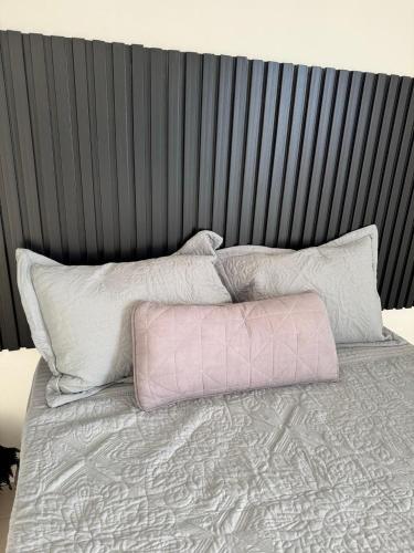 1 cama con 3 almohadas y cabecero negro en Entre vientos, en La Porteña