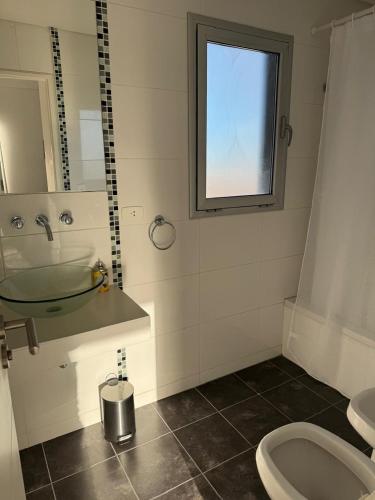 Un baño con lavabo, inodoro y ventana. en Entre vientos, en La Porteña