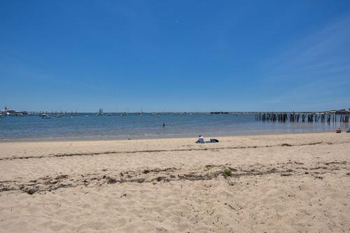 a person sitting on a beach near the water at NEW AC 1 Bedroom w Private Deck & Patio in Provincetown
