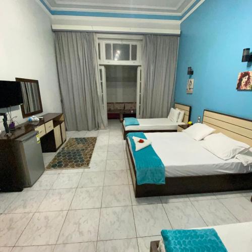 Una habitación de hotel con dos camas y un televisor. en Hostgram Home - Talaat Harb Square, en El Cairo