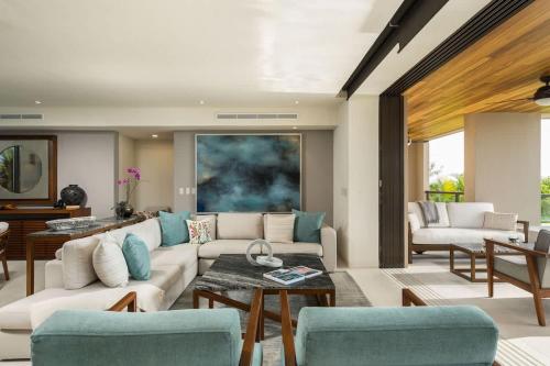 een woonkamer met een witte bank en blauwe stoelen bij Tropical Oceanview Condo Punta Mita in Punta Mita