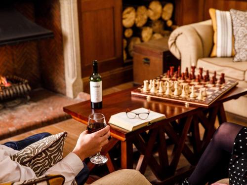 dos personas jugando al ajedrez con una copa de vino en Mercure Oxford Hawkwell House Hotel, en Oxford