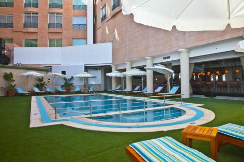 una piscina en un hotel con sillas y sombrillas en Hôtel César Palace en Sousse