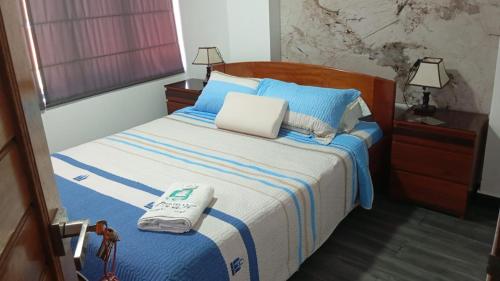 een slaapkamer met een bed met blauwe en witte lakens bij Hotel RUAH in Tumbes