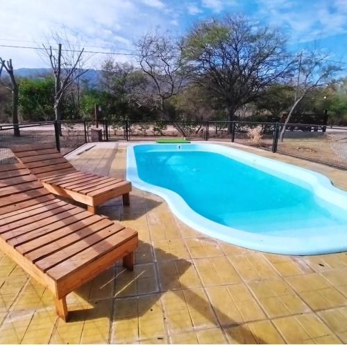 Una piscina con dos bancos de madera alrededor. en Cabañas Peñihue, en Carpintería