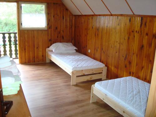 a room with two beds in a wooden wall at Chata Posudov - Lipno in Frymburk