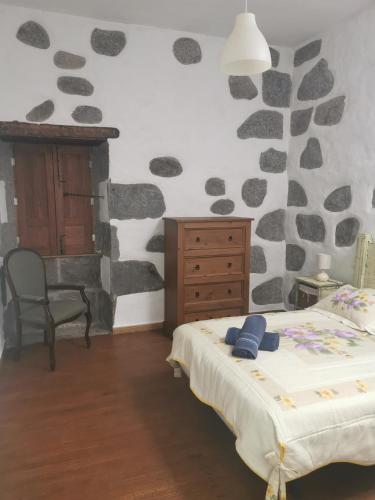 a bedroom with a bed and a rock wall at Casa Gloria, encanto canario entre montaña y mar in Arucas