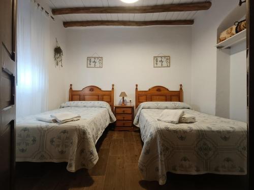 two beds in a room with white walls and wooden floors at Casa Rural Abuela Remedios in Segura de León