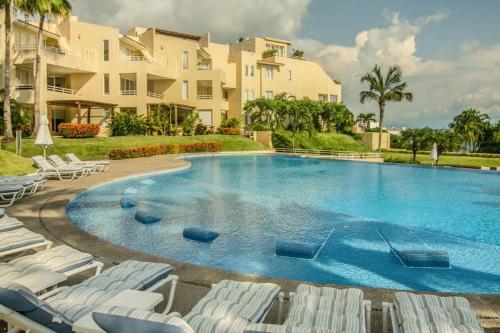 a large swimming pool with chairs and a building at Oceanview Condo in Faro de Mita in Punta Mita