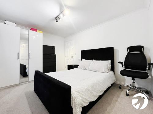 a bedroom with a black bed and a black chair at 6 Bed Longstay & Shortstay property with Wifi & parking sleeps 14 in Chatham