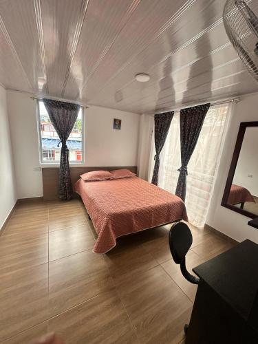 a bedroom with a bed and two windows at La Casa de Oliva in Norcasia
