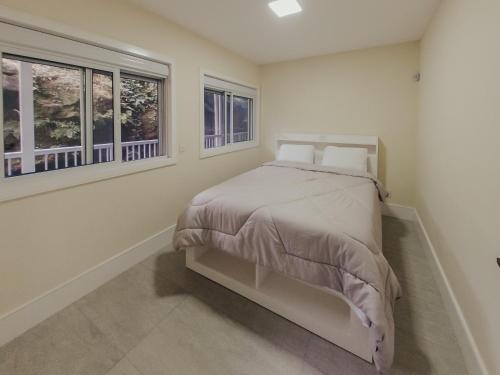 a bedroom with a bed and two windows at Recanto das Pedras Lodgin in Santa Maria do Erval