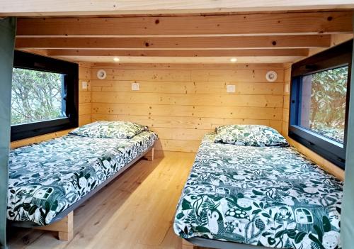 two beds in a room with two windows at Tiny House cosy pour une parenthèse nature in Marcilly-sur-Eure