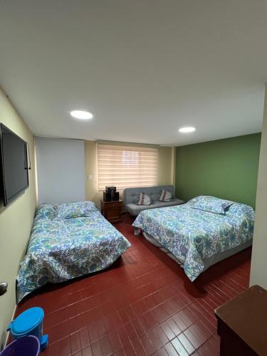 una habitación con dos camas y un sofá en The Mountain Apto House, en Bogotá