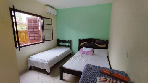 una piccola stanza con due letti e una finestra di Pousada dos Comerciários Prainha de Mambucaba PARATY a Parati
