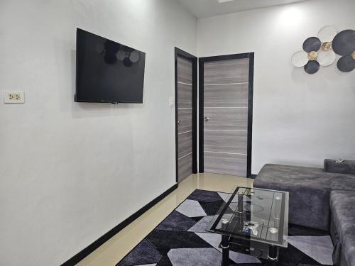 Ban Nong ChaengCute Villa 350m to Bang Tao Beach, sleeps up to 6的客厅里有一张沙发，墙上有一台电视