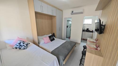 a small bedroom with two beds and a television at Apartamento no Centro de Mongaguá, perto da praia! in Mongaguá