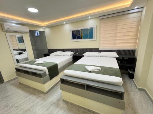 um quarto com duas camas e um espelho em Hotel Magistral Suiter em Quibdó