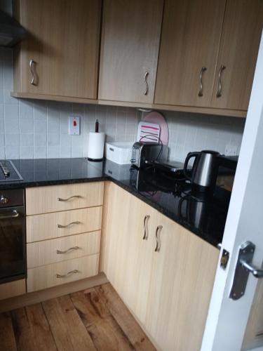 a kitchen with wooden cabinets and black counter tops at Nature City Blend Cozy 3 BR in Belfast