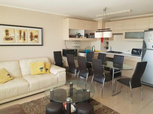 a living room with a couch and a table and a kitchen at Depto Laguna Vista Hermoso Comodo Familiar in Algarrobo