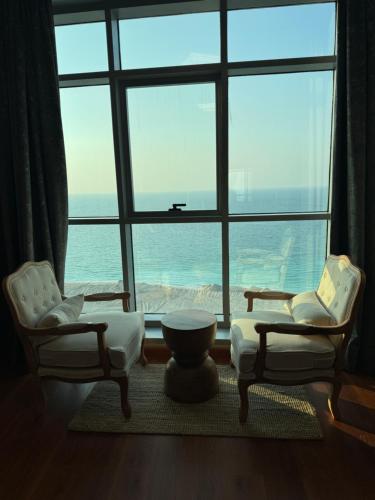 a living room with two chairs and a large window at Luxury Sea View Apartment Pool & Gym&jacuzzi in Ajman
